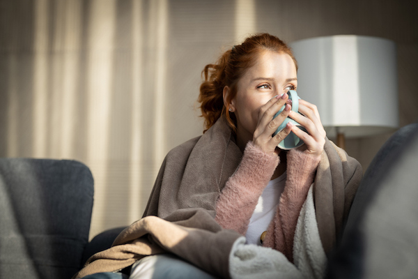 giovane donna su divano beve tazza di tè