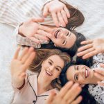 Un gruppo di amiche nel letto in pigiama che previene il rischio di infezioni intime adottando una corretta igiene intima e indossando biancheria di cotone