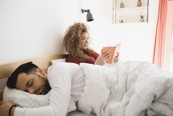 Coppia con donna che legge e uomo che dorme di pomeriggio