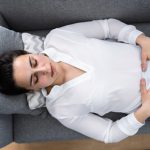 Donna con infezione intima che si rilassa sul divano di casa