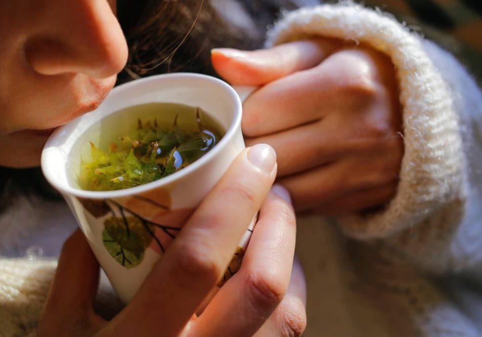 Giovane donna beve tisana per alleviare i sintomi della cistite