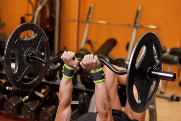 Uomo che esegue una serie di french press in palestra