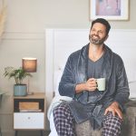 Uomo seduto a letto lieto di dormire bene