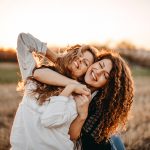 Giovani amiche che si abbracciano e si godono i benefici della vitamina D, trascorrendo una giornata all’aria aperta