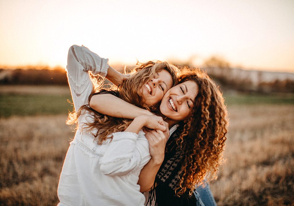 Giovani amiche che si abbracciano e si godono i benefici della vitamina D, trascorrendo una giornata all’aria aperta