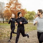 Amici che praticano jogging al parco, evitando l’eccessiva sedentarietà e prevenendo l’insorgenza di artrosi al ginocchio in età avanzata