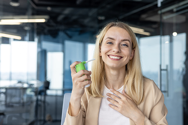 Donna in ufficio che assume FANS e inala spray per combattere il mal di gola