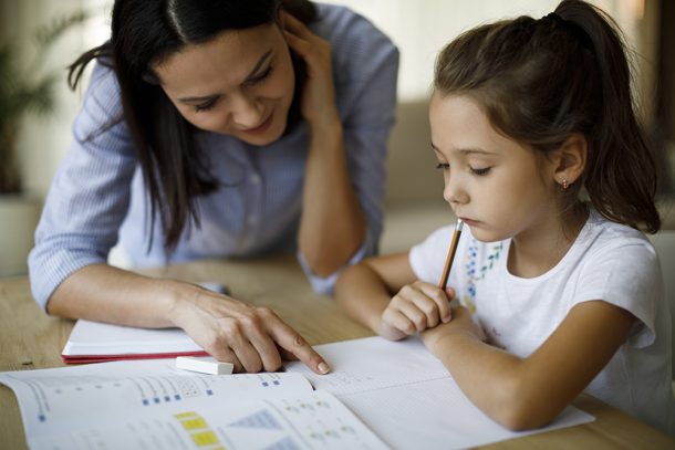 Bambina con disturbi del linguaggio che esegue i compiti a casa con il supporto della mamma