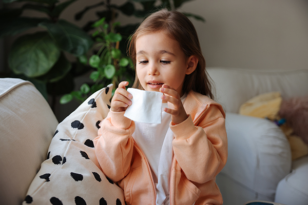 Bambina che copre bocca e naso durante uno starnuto e favorisce la guarigione da stomatite alla bocca