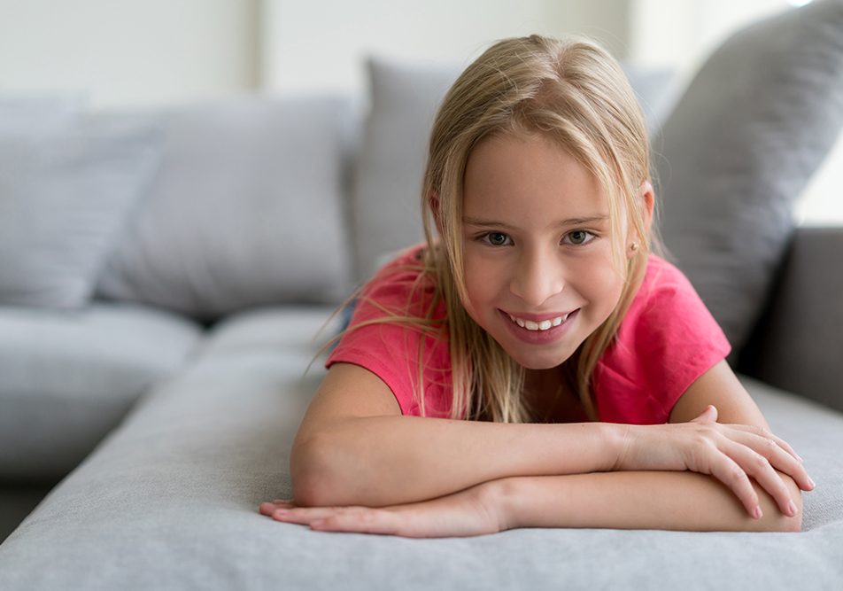 bambina-gioiosa-sul-divano-di-casa-guarigione-da-infiammazione-del-palato Bambina gioiosa sul divano di casa guarita dall’infiammazione del palato