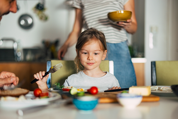 Bambina che mangia una colazione al tavolo ricca di calcio, insieme alla sua famiglia