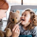 Bambina sorridente che si sottopone al tampone per lo streptococco dalla pediatra