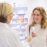 Caregiver che riceve il farmaco al bancone della farmacia munita di ricetta farmaci con ticket di esenzione