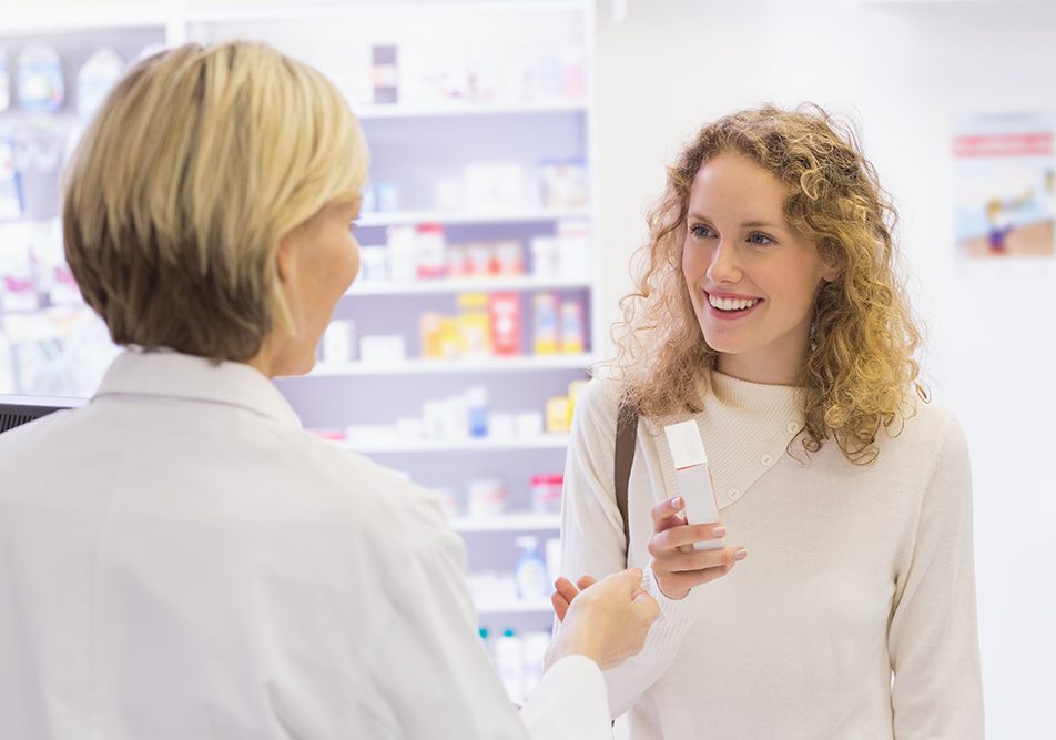 Caregiver che riceve il farmaco al bancone della farmacia munita di ricetta farmaci con ticket di esenzione