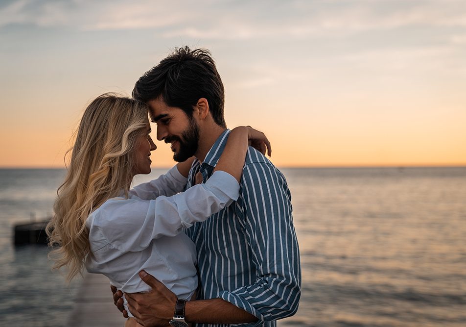 Coppia abbracciata al mare che rischia la trasmissione delle placche in gola durante il momento del bacio
