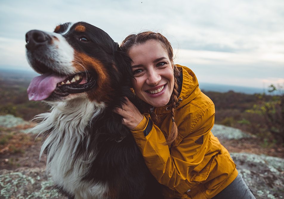 Donna che abbraccia il suo cane e che previene l’insorgenza di un tumore nel cane adottando uno stile di vita sano