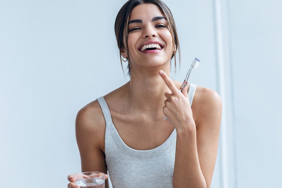 Donna che risciacqua i denti con una miscela al bicarbonato di sodio per contribuire alla pulizia del cavo orale e allo sbiancamento dei denti