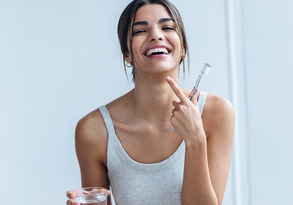 Donna che risciacqua i denti con una miscela al bicarbonato di sodio per contribuire alla pulizia del cavo orale e allo sbiancamento dei denti