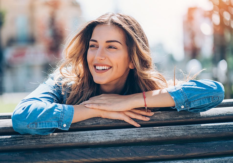 Donna sorridente al parco cittadino, che conduce uno stile di vita sano ed equilibrato per la prevenzione delle bolle sul palato