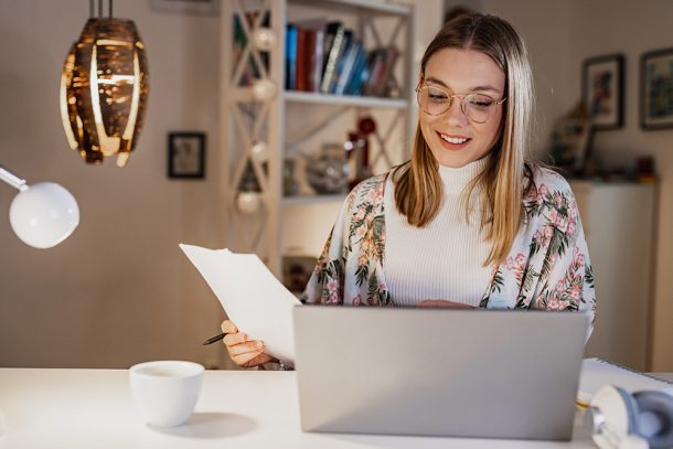 Donna davanti al computer che legge i referti e la sua prenotazione con l’impegnativa del medico