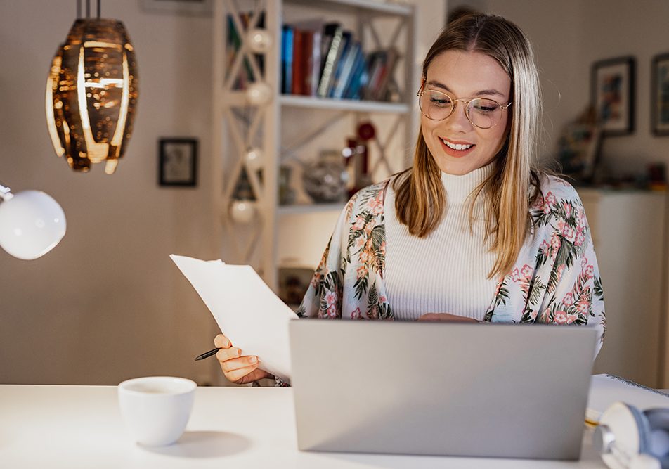 Donna davanti al computer che legge i referti e la sua prenotazione con l’impegnativa del medico