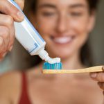 Donna che applica dentifricio su spazzolino in bamboo per la sua igiene orale quotidiana
