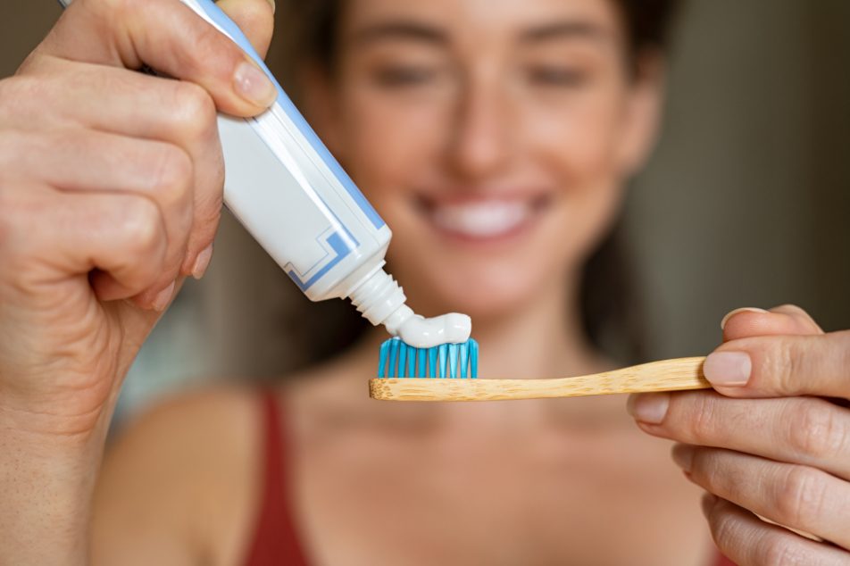 donna-dentifricio Donna che applica dentifricio su spazzolino in bamboo per la sua igiene orale quotidiana