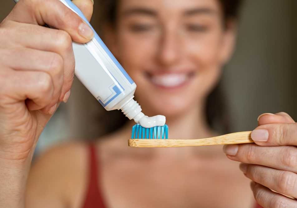 donna-dentifricio Donna che applica dentifricio su spazzolino in bamboo per la sua igiene orale quotidiana