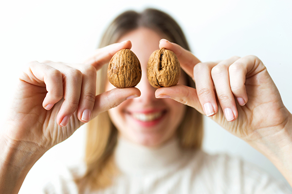 Donna che consuma noci, ovvero frutta secca, per contribuire alla salute dell’apparato digerente