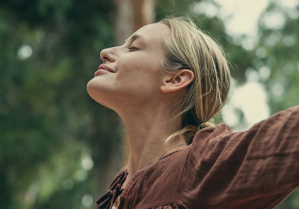 Donna immersa nella natura che si rigenera respirando l’aria fresca ed il profumo delle erbe aromatiche