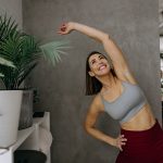 Donna sorridente che pratica degli esercizi di stretching per le spalle