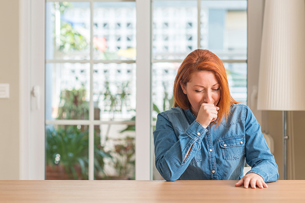 Donna che previene il batterio dello streptococco coprendosi la bocca mentre starnutisce