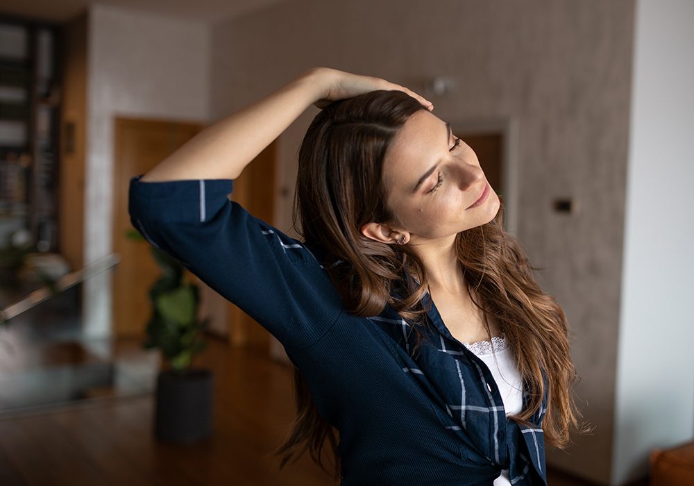 Donna con prurito al collo che pratica stretching per alleviare la tensione cervicale