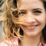 Donna sorridente all’aria aperta con placche in gola senza febbre