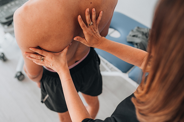 Fisioterapista che visita il paziente con spalla lussata nello studio medico, studiando gli esercizi adatti per il suo recupero
