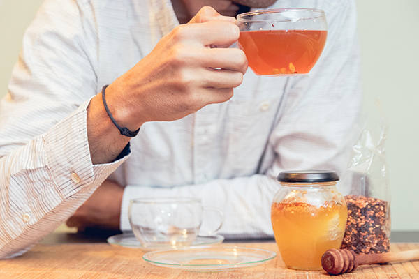 Giovane uomo beve un infuso in acqua calda per depurarsi da un’infezione urinaria