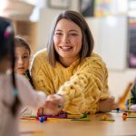 Maestra sorridente insieme ai suoi piccoli alunni, durante il periodo di incubazione dello streptococco