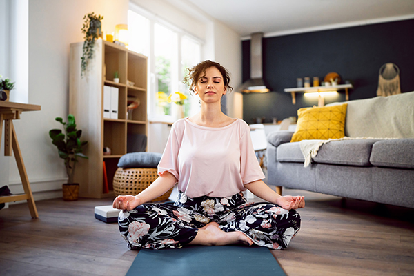 Donna che pratica la meditazione sul tappetino nel salotto di casa