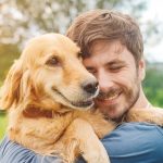 Padrone che abbraccia il suo cane al parco, adottando uno stile di vita attivo come prevenzione del tumore della pelle