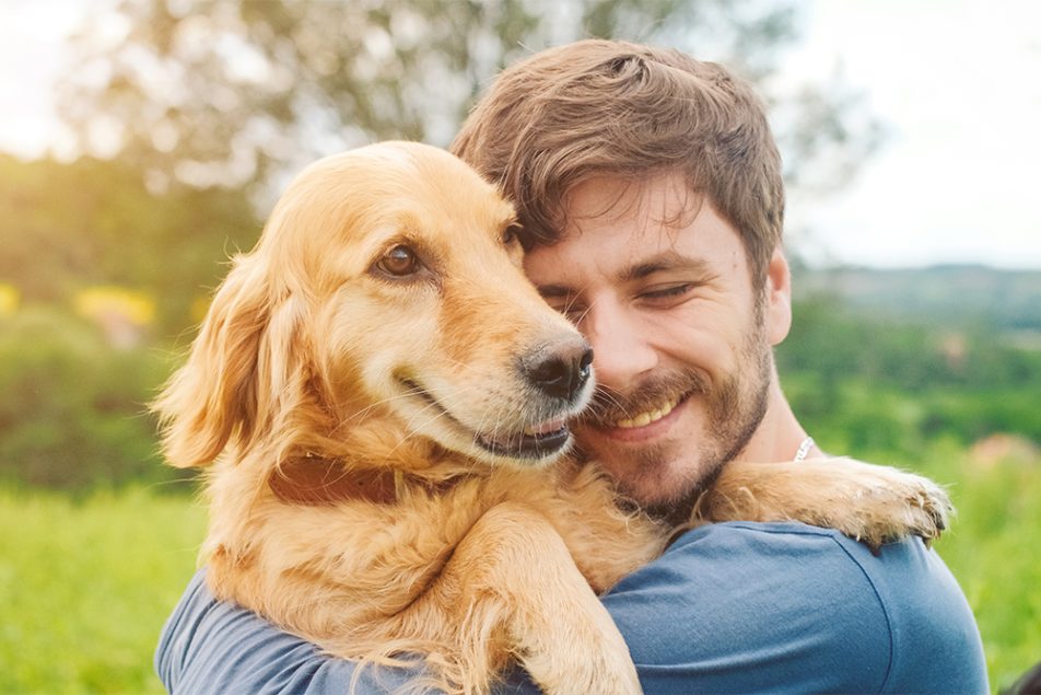 Padrone che abbraccia il suo cane al parco, adottando uno stile di vita attivo come prevenzione del tumore della pelle
