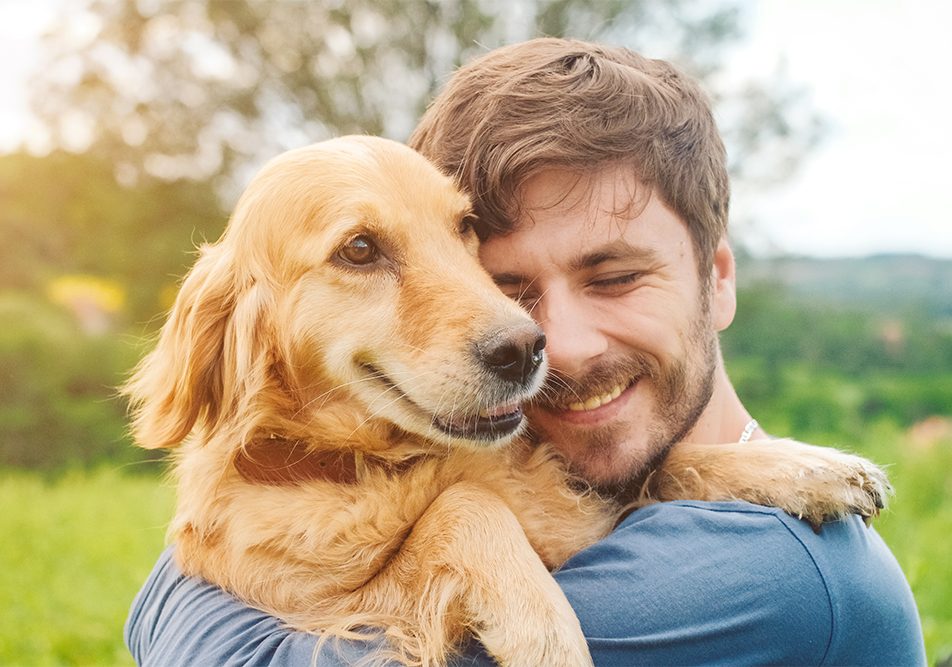 Padrone che abbraccia il suo cane al parco, adottando uno stile di vita attivo come prevenzione del tumore della pelle