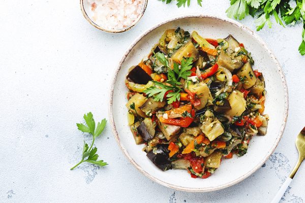Piatto con caponata di melanzane al forno e prezzemolo fresco, servito su un tavolo bianco