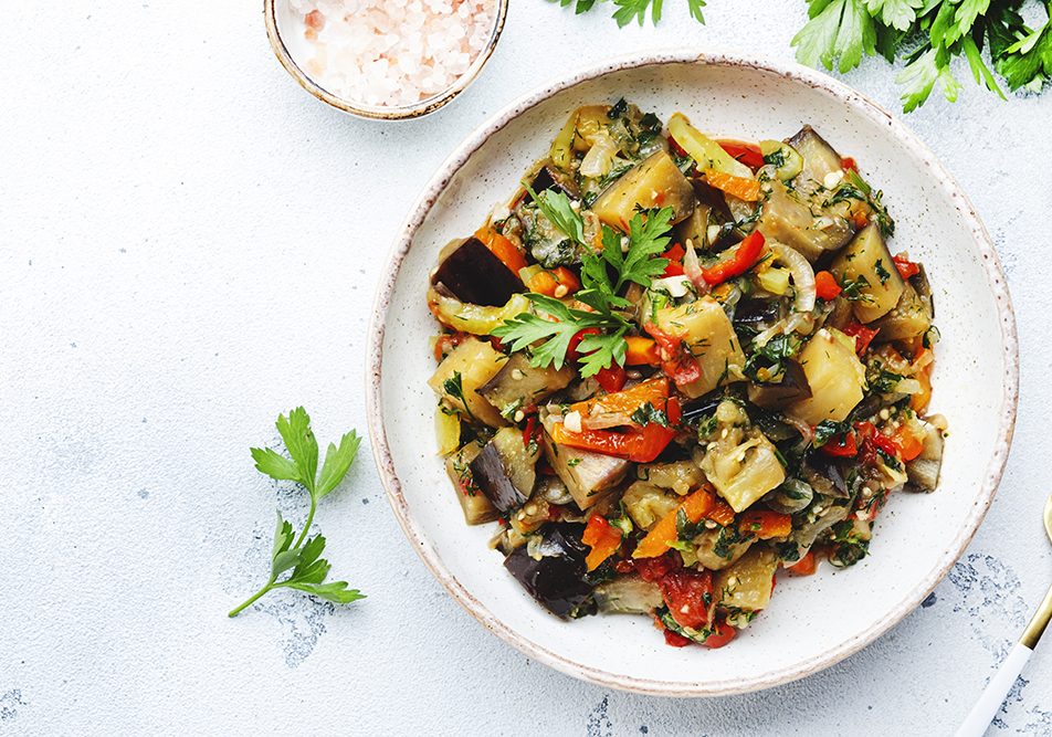 Piatto con caponata di melanzane al forno e prezzemolo fresco, servito su un tavolo bianco