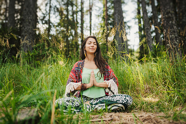 Donna che pratica yoga nella natura, una delle tecniche di rilassamento promossa dalla naturopatia