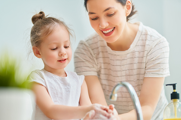 Madre che previene le infezioni, come la varicella nei bambini, insegnando alla figlia come lavarsi le mani