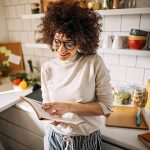 Giovane donna che consulta un ricettario per la preparazione di un pasto ricco di proteine vegetali