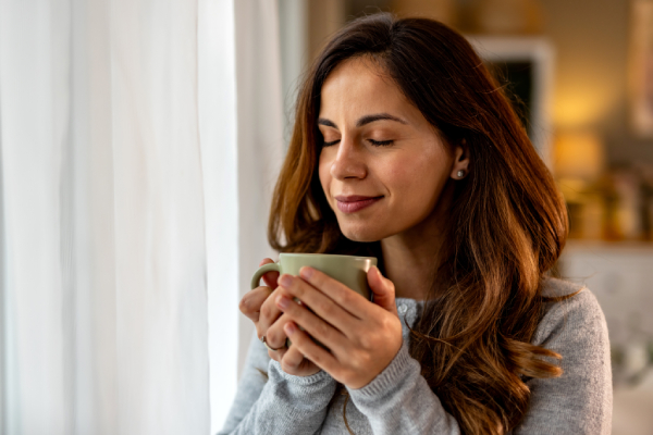 Giovane donna beve tisana calda, tra i rimedi per il mal di gola