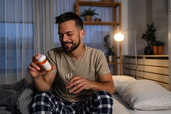 Uomo a letto che assume Augmentin evitando l’alcol per l’efficacia del trattamento