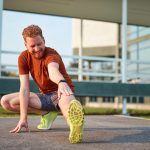 Giovane uomo che avverte dolore al ginocchio durante una sessione di stretching al parco cittadino