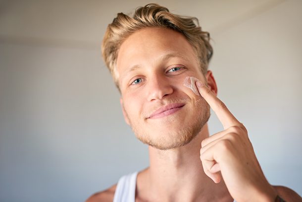 uomo-osservando-infiammazione-neo-viso Giovane uomo che osserva davanti allo specchio l’infiammazione di un neo sul suo viso